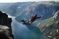 Man base jumping off a cliff over a river to signify 360 degree view experience stock photo
