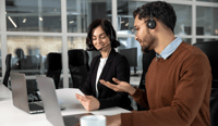 Business partners sitting at table in boardroom working on project with laptops stock photo, Utilising Generative AI in sales concept.jpg