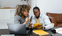 Two people sat at a desk on a tablet stock photo as AI proof of concept concept