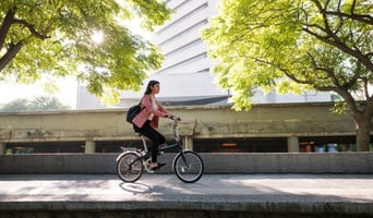 Young woman going to work by bike stock photo to display culture of sustainability concept