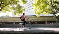 Young woman going to work by bike stock photo to display culture of sustainability concept