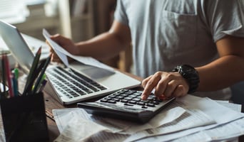 Men is calculating the cost of the bill. He is pressing the calculator. Concept of cheat sheet for traditional vs e-invoicing stock photo.jpg