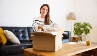Smiling woman packing preloved clothes for resale, embracing sustainable fashionindoor, cheerful stock photo