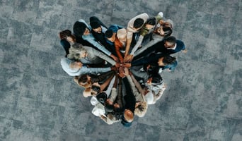 Top view of a a heart shape of people, showing unity and teamwork as post merger integration culture following M&A concept stock photo.jpg