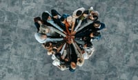 Top view of a a heart shape of people, showing unity and teamwork as post merger integration culture following M&A concept stock photo.jpg
