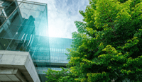 Sustainable green building. Eco-friendly building. Sustainable glass office building with trees for reducing carbon dioxide. Green company office with green environment. ESG regulation at publishing company concept. stock photo