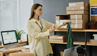 Side view of young woman with smartphone taking photo of shirt on hangers stock photo