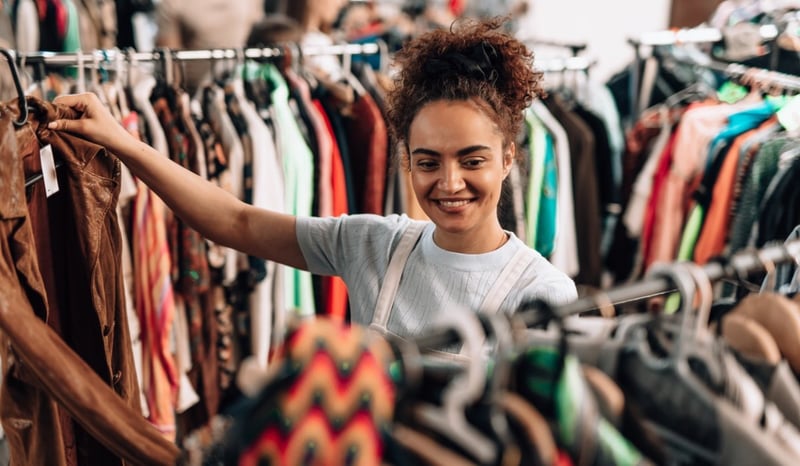 Image for Young woman choosing clothes in a second hand shop promoting sustainable fashion stock photo
