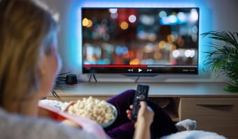 Woman relaxing at home in evening and watching TV as media subscription models concept stock photo