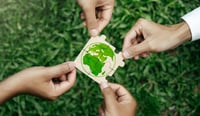 Four hands holding a jigsaw puzzle of a world as four sustainability operating model options concept