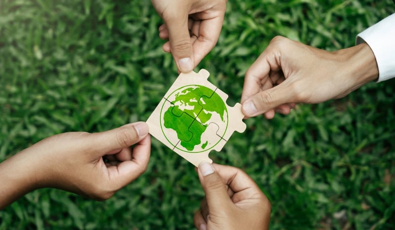 Image for Four hands holding a jigsaw puzzle of a world as four sustainability operating model options concept