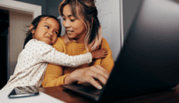 Little girl embracing her mom in her home office as working woman in leadership concept stock photo