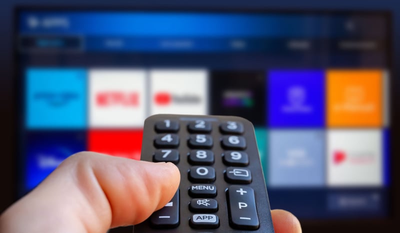 Image for A man is holding a remote control of a smart TV in his hand. In the background you can see the television screen with streaming entertainment apps for video on demand stock photo