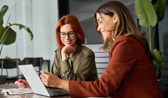 Happy female colleagues working on a computer as concept for human imperative in an AI world