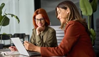 Happy female colleagues working on a computer as concept for human imperative in an AI world