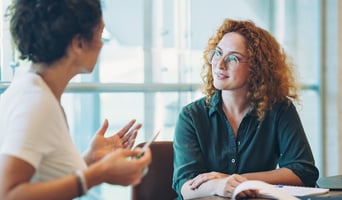 young woman having pay conversation with colleague in office 