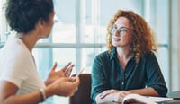 young woman having pay conversation with colleague in office 