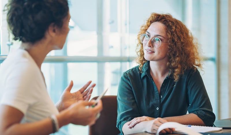 Image for young woman having pay conversation with colleague in office 