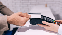 Hands of a young man which makes contactless payment for clothes that he bought in a boutique stock photo