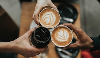 Three coffees cheersing with hands to signify coffee shop customer experience concept