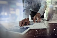 A hand pointing at indication of revenue growth on a laptop screen