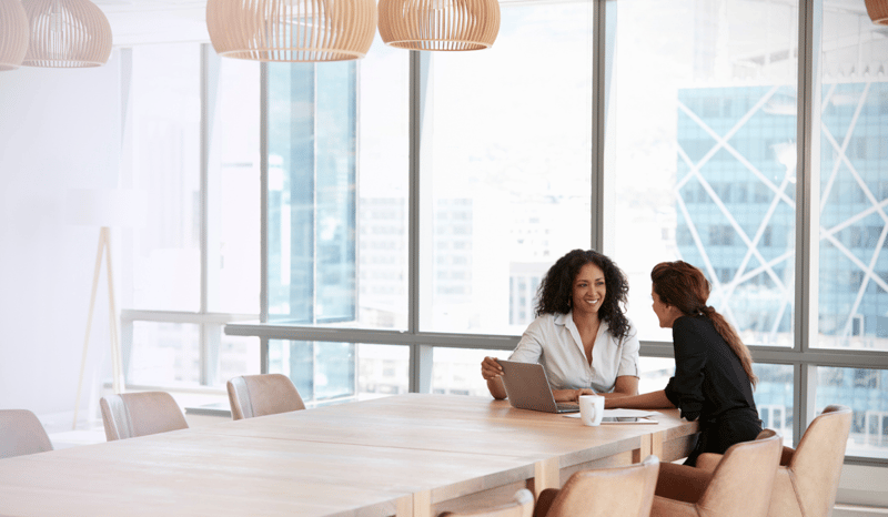 Image for Two women in a boardroom using laptop to unlock business potential through purpose in a meeting