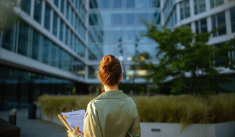 Seen from behind business woman holding ESG legislation near office building post-merger stock photo